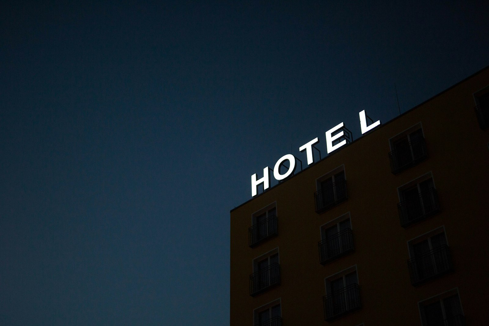 Enseigne lumineuse « Hotel » sur une façade, à la tombée de la nuit